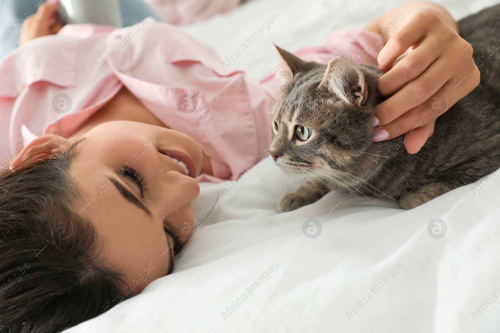 Photo of Young woman with cute cat on bed. Pet and owner