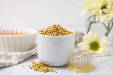 Photo of Fresh bee pollen granules and dipper with honey on white table, closeup