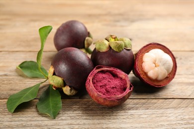 Photo of Purple mangosteen powder and fruits on wooden table