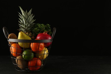 Fresh ripe fruits in metal basket on black table, space for text