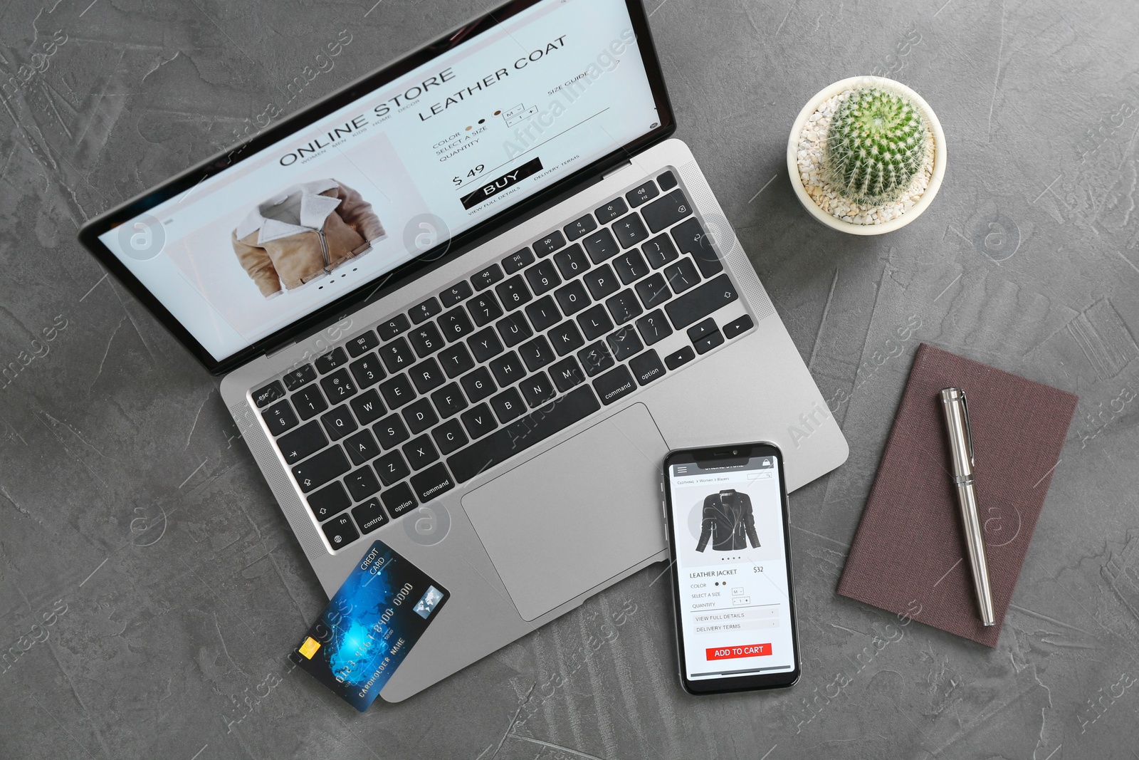 Photo of Online store website on laptop screen. Computer, smartphone, stationery, credit card and cactus on grey table, flat lay