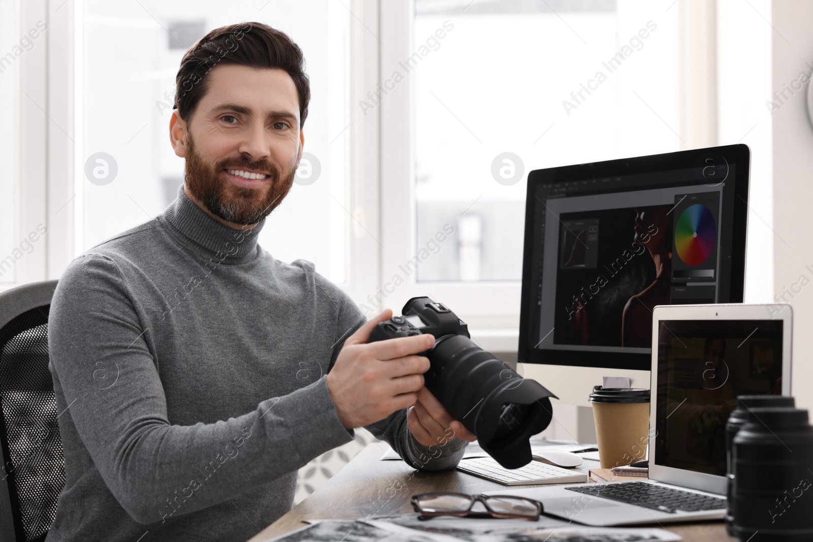 Photo of Professional photographer with digital camera at table in office