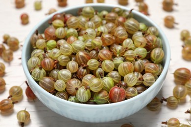 Photo of Bowl with fresh ripe gooseberries on white table, closeup