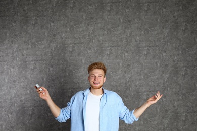 Photo of Young man with air conditioner remote on grey background