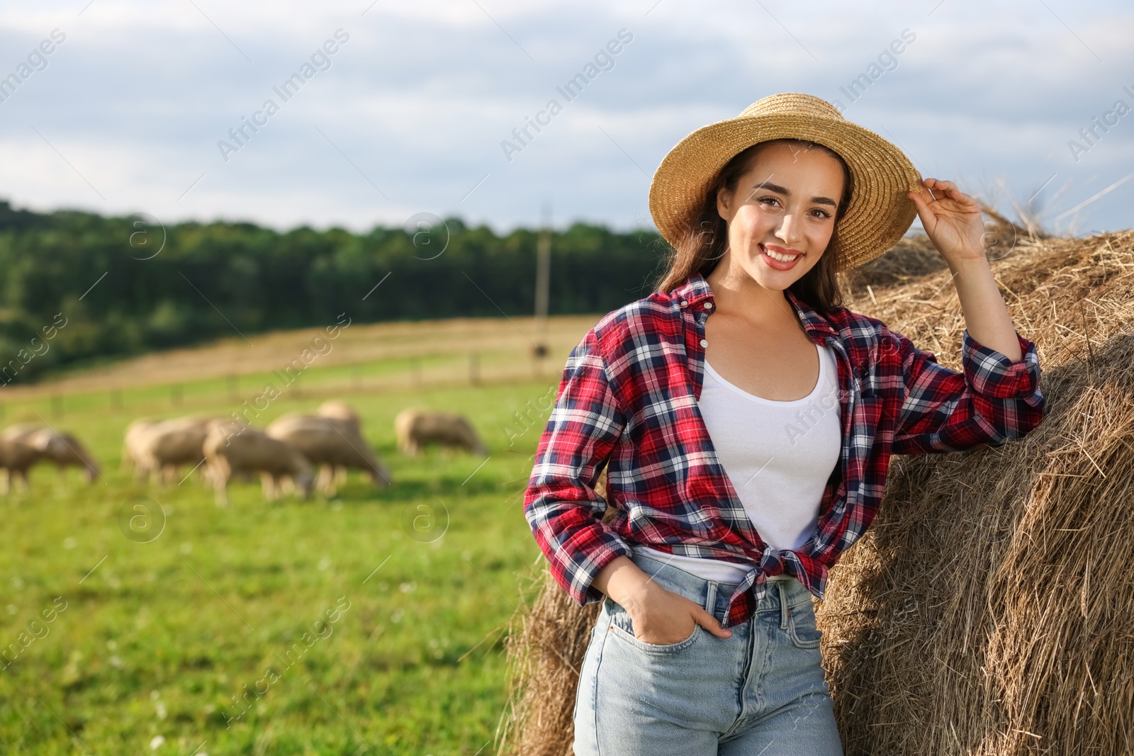 Photo of Smiling farmer near hay bale outdoors. Space for text