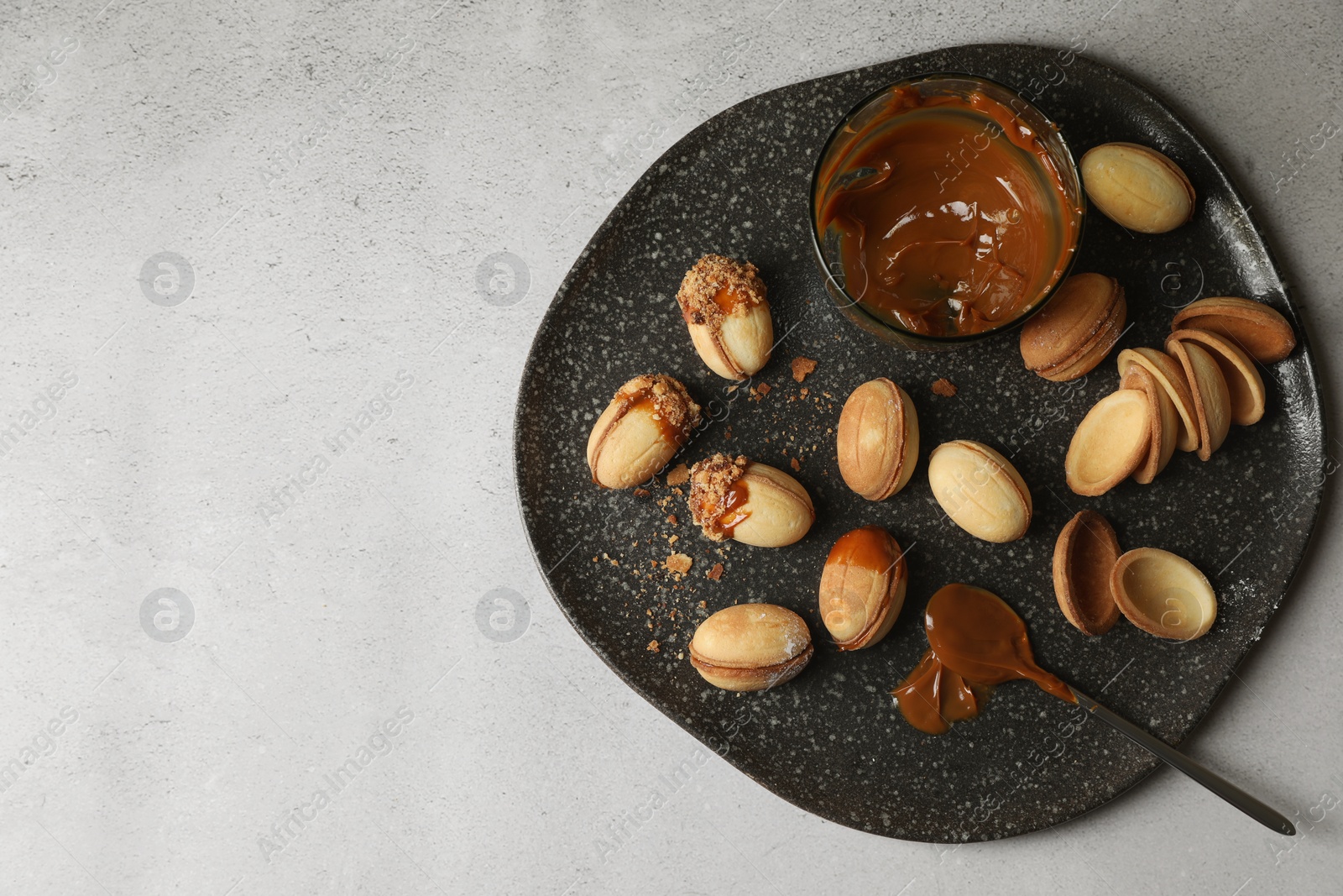 Photo of Delicious walnut shaped cookies with condensed milk on grey table, top view. Space for text