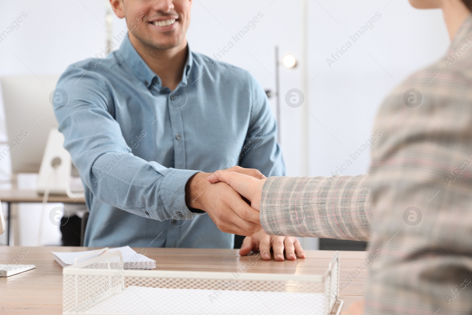 Photo of Employee shaking hands with intern in office, closeup