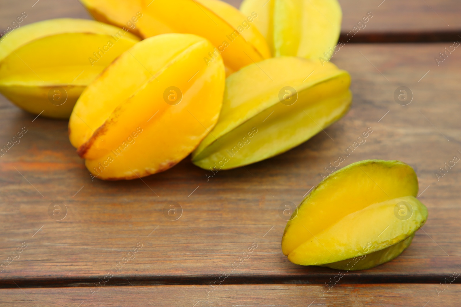 Photo of Delicious ripe carambolas on wooden table, closeup