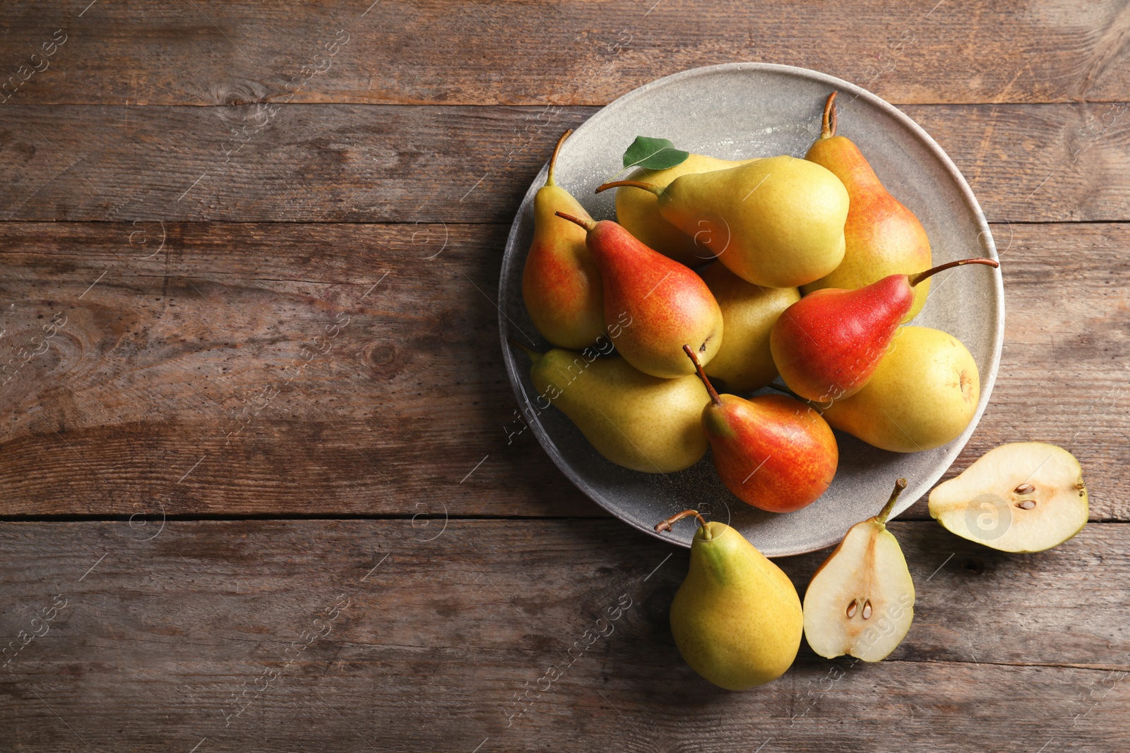 Photo of Plate with ripe pears on wooden background, top view. Space for text