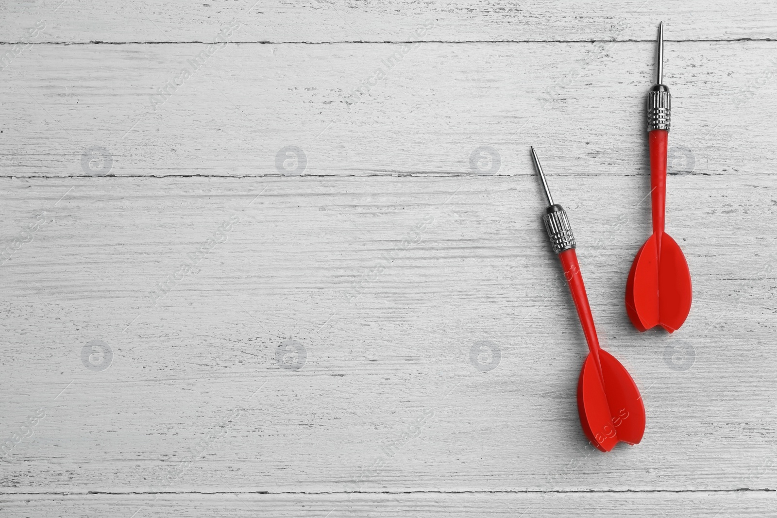 Photo of Red dart arrows on white wooden table, flat lay with space for text