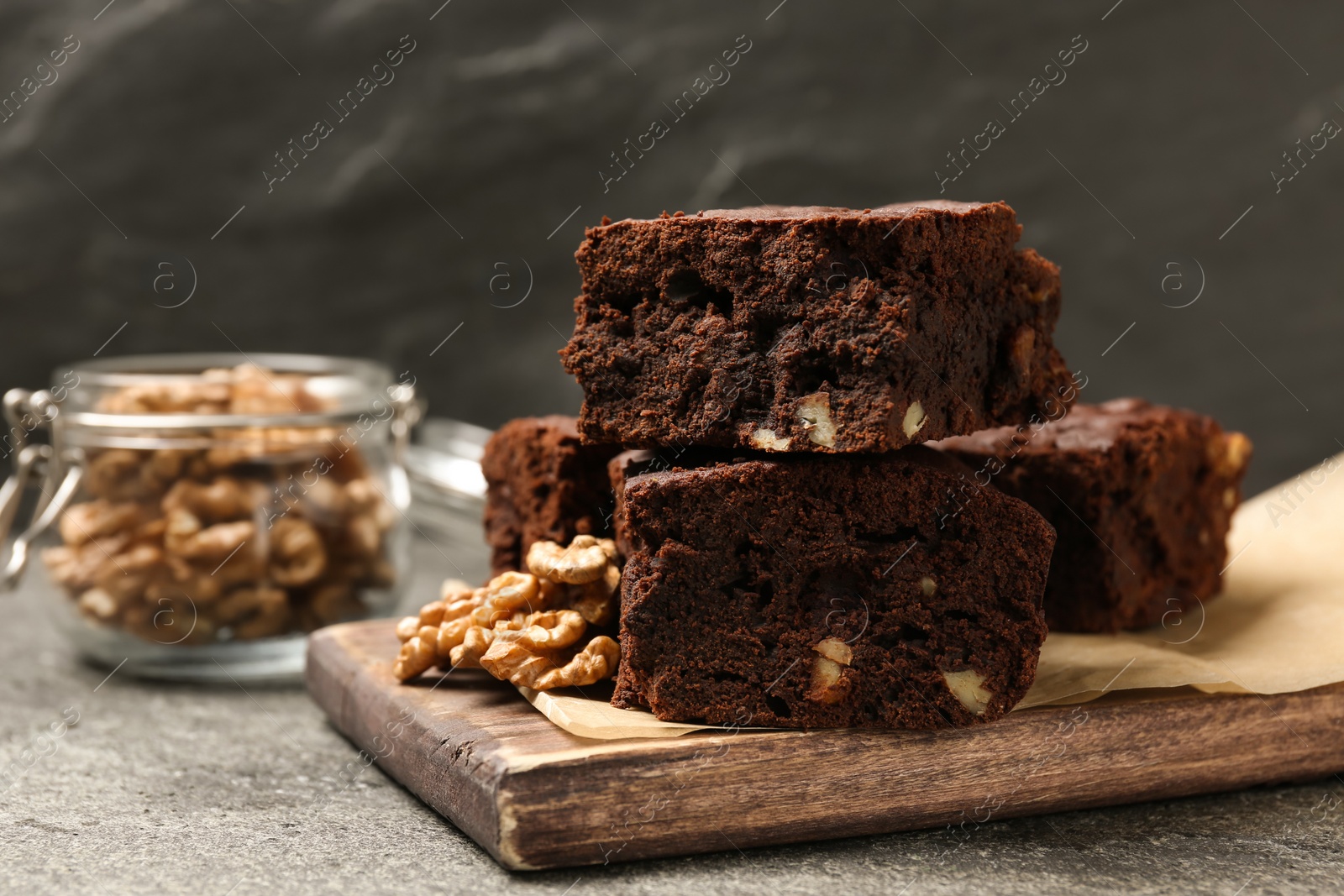 Photo of Delicious chocolate brownies with nuts on grey table