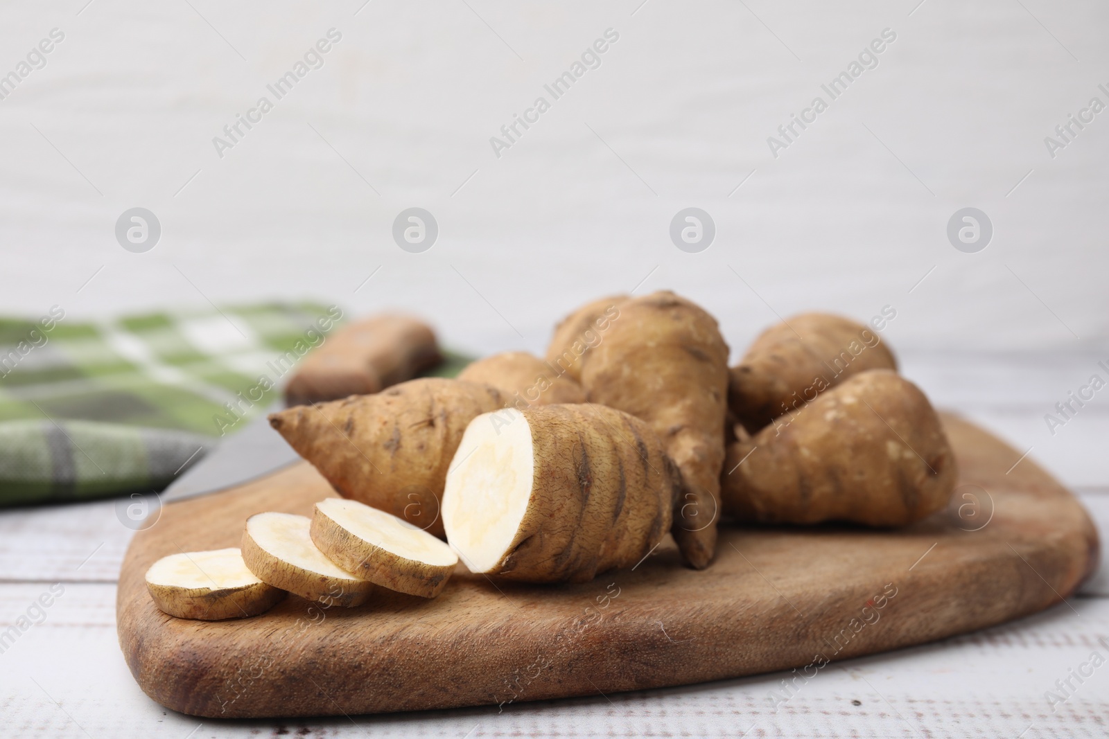 Photo of Whole and cut turnip rooted chervil tubers on wooden table