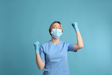 Photo of Emotional doctor with protective mask on light blue background. Strong immunity concept