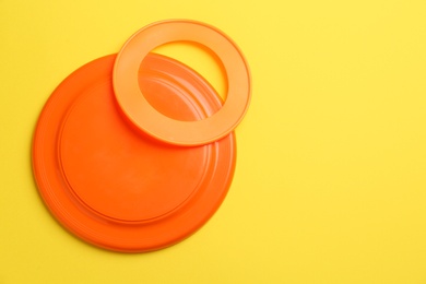 Photo of Plastic frisbee disk and ring on yellow background, flat lay. Space for text