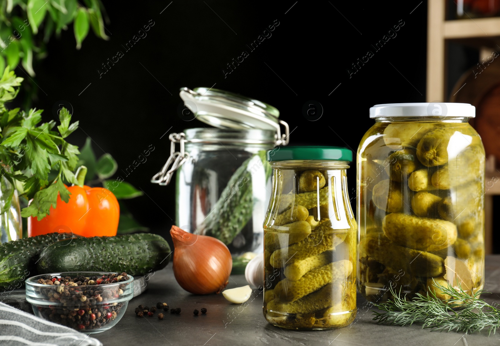 Photo of Glass jars of pickled cucumbers on grey table