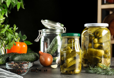 Photo of Glass jars of pickled cucumbers on grey table