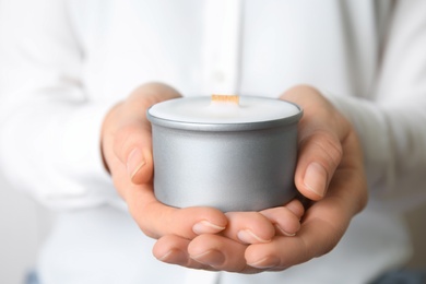 Photo of Woman holding candle with wooden wick, closeup