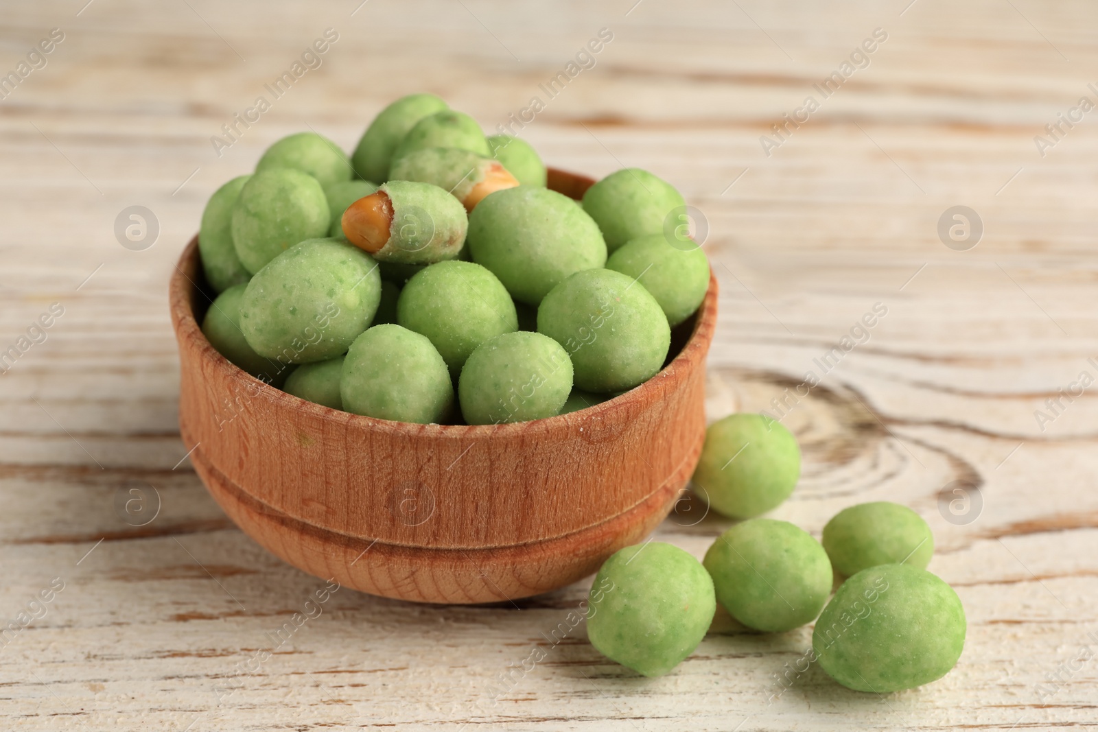 Photo of Tasty wasabi coated peanuts on white wooden table, closeup