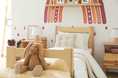 Photo of Toy bunny on faux fur in modern girl's bedroom. Interior design