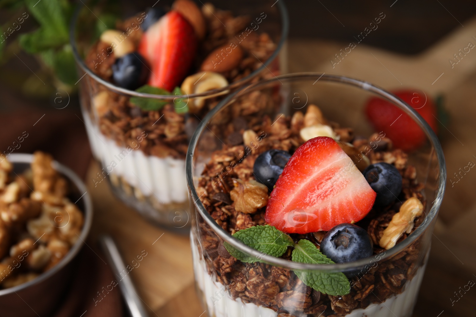 Photo of Tasty granola with berries, nuts and yogurt on table, closeup