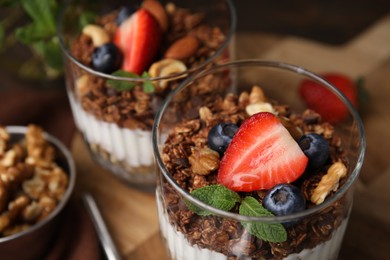 Photo of Tasty granola with berries, nuts and yogurt on table, closeup