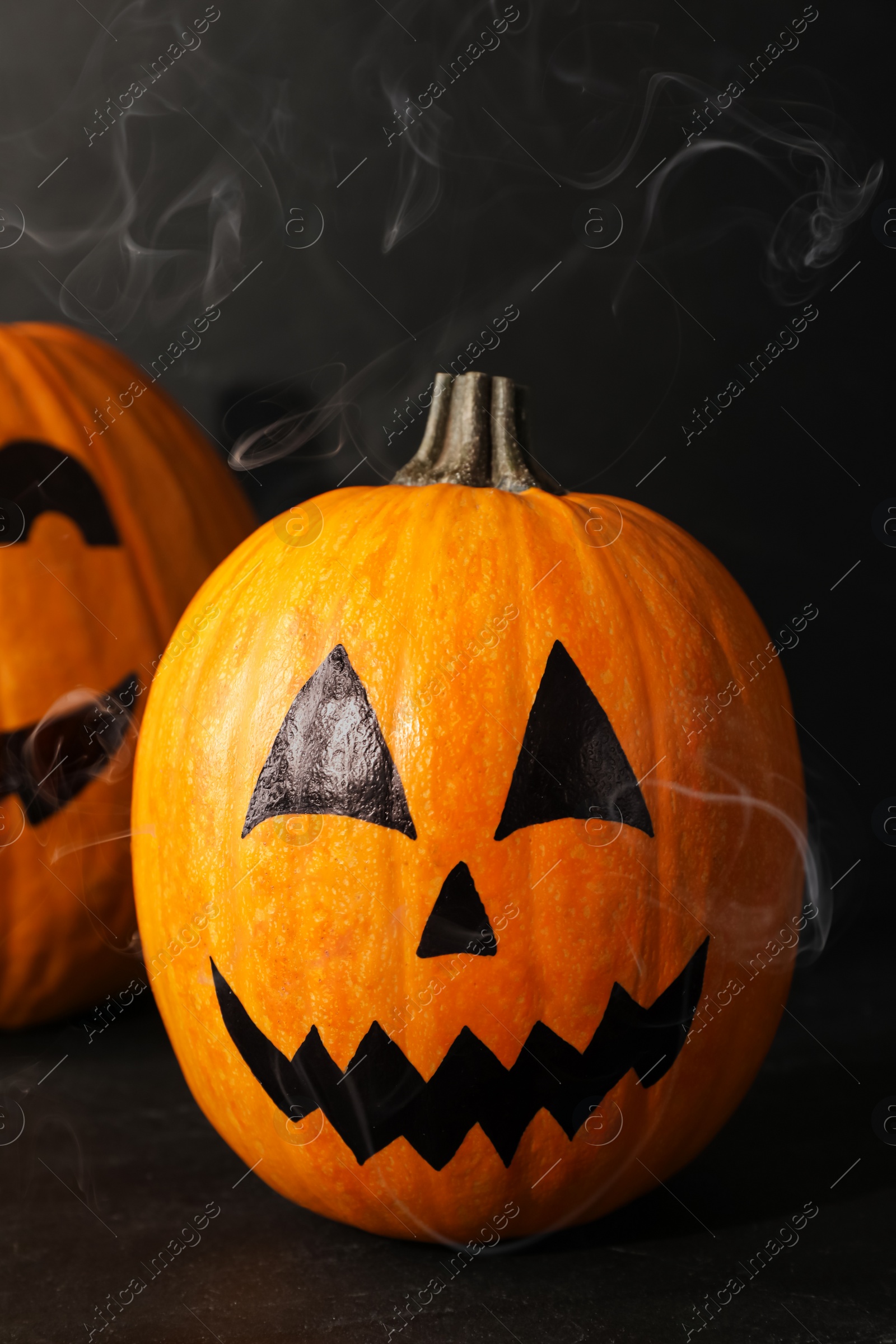 Photo of Pumpkins with drawn spooky faces on dark background. Halloween celebration