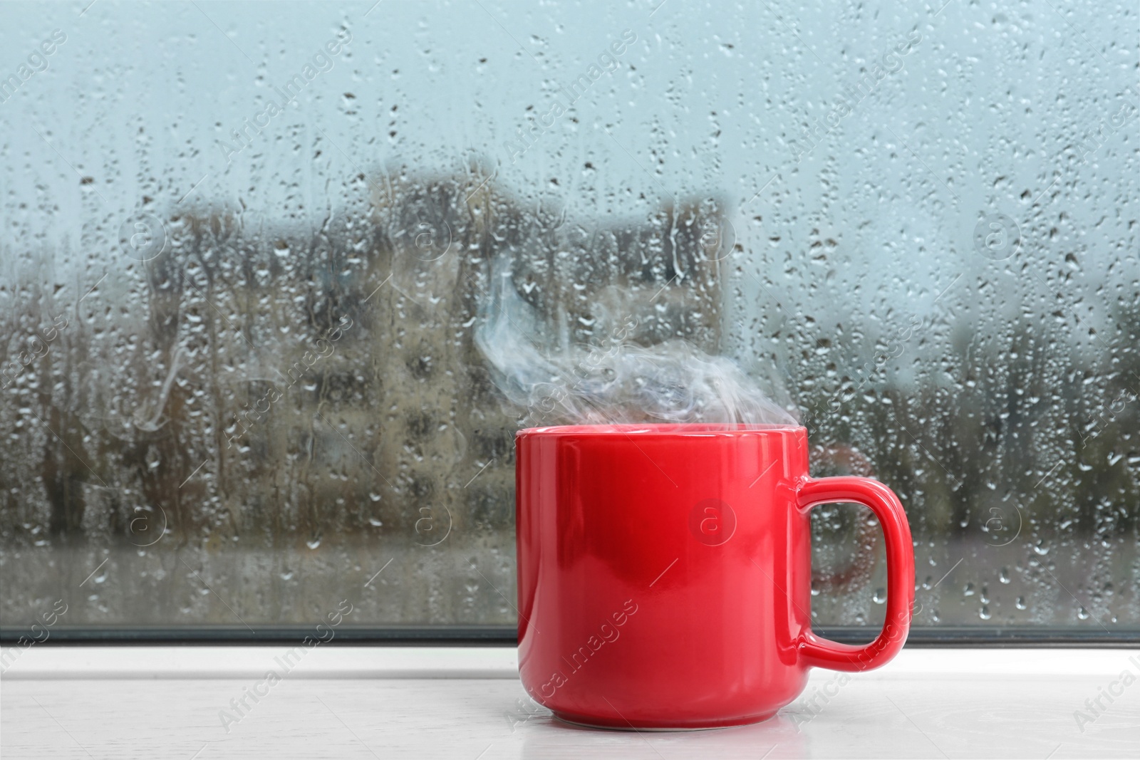 Photo of Cup of hot drink on white windowsill. Rainy weather