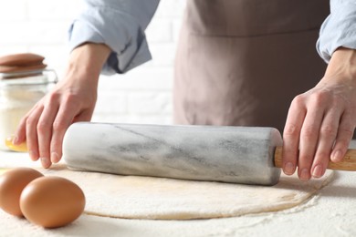 Photo of Woman rolling raw dough at table, closeup