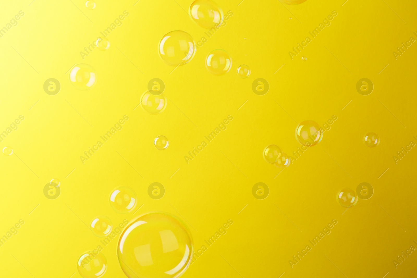 Photo of Beautiful transparent soap bubbles on yellow background