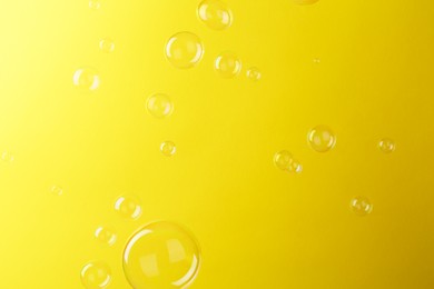 Photo of Beautiful transparent soap bubbles on yellow background