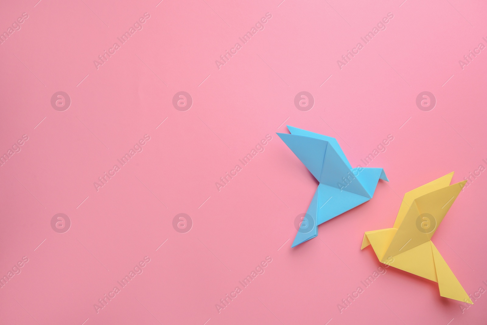 Photo of Beautiful colorful origami birds on pink background, flat lay. Space for text