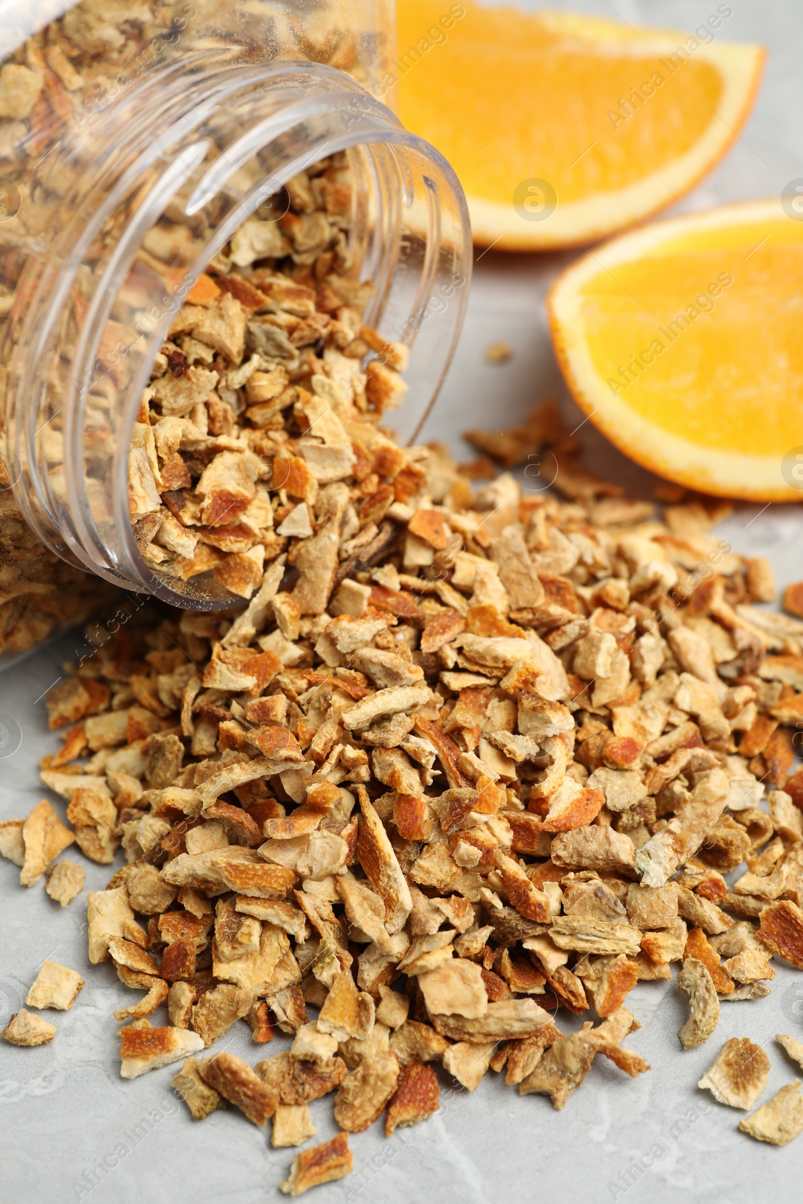 Photo of Jar with dried orange zest seasoning and fresh fruit on light grey table, closeup