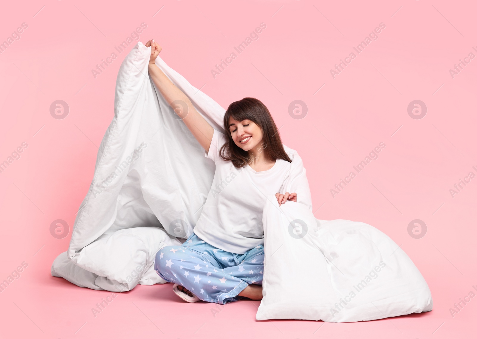 Photo of Happy woman in pyjama wrapped in blanket on pink background