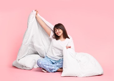 Photo of Happy woman in pyjama wrapped in blanket on pink background