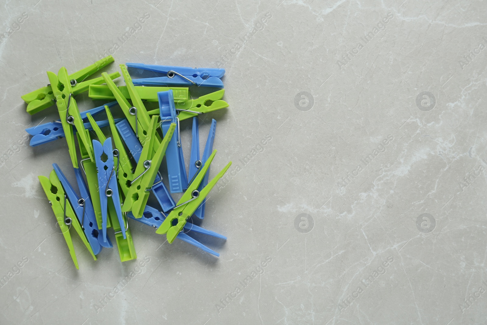 Photo of Colorful plastic clothespins on light grey marble background, flat lay. Space for text