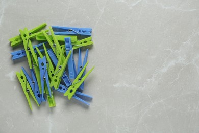 Colorful plastic clothespins on light grey marble background, flat lay. Space for text