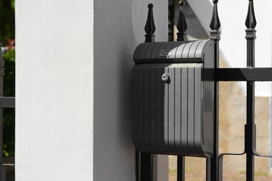 Dark metal letter box on fence outdoors