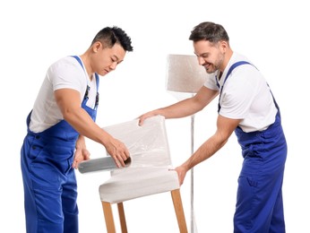 Photo of Workers wrapping chair in stretch film on white background