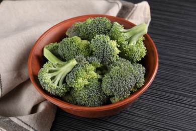 Bowl with fresh raw broccoli on black wooden table