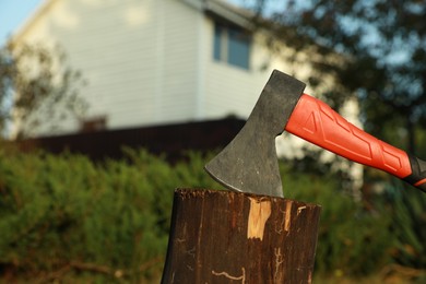 Photo of Metal axe in wooden log on backyard, closeup. Space for text