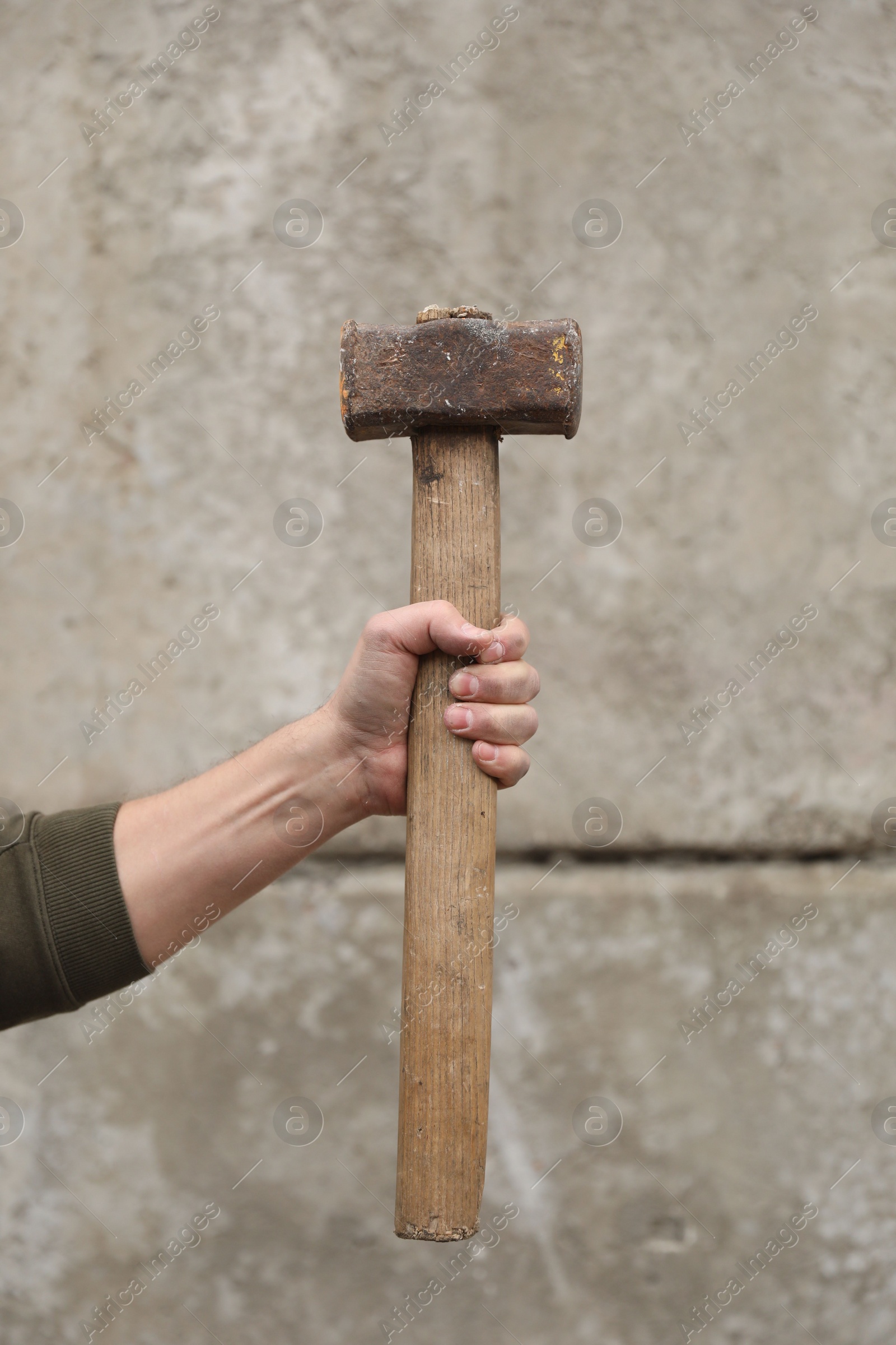 Photo of Man with sledgehammer near grey wall, closeup