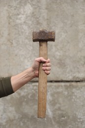 Photo of Man with sledgehammer near grey wall, closeup