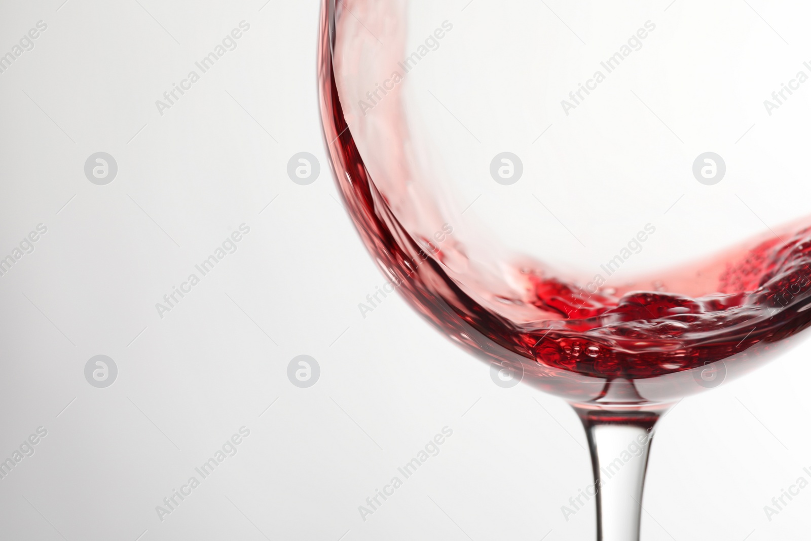 Photo of Pouring red wine into glass on light background, closeup