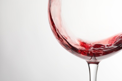 Photo of Pouring red wine into glass on light background, closeup