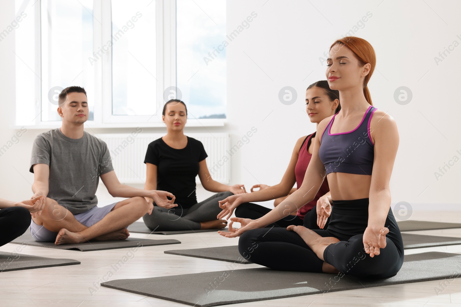 Photo of Group of people practicing yoga on mats indoors