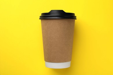 Photo of One paper cup on yellow background, top view. Coffee to go