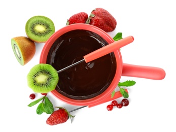 Fondue pot with dark chocolate, fruits and berries on white background, top view