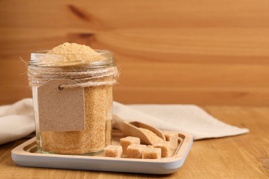 Jar with brown sugar on wooden table, space for text