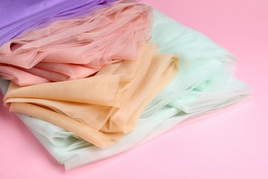 Photo of Beautiful colorful tulle fabrics on pink background