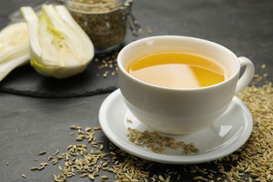 Photo of Aromatic fennel tea in cup and seeds on black table, closeup. Space for text